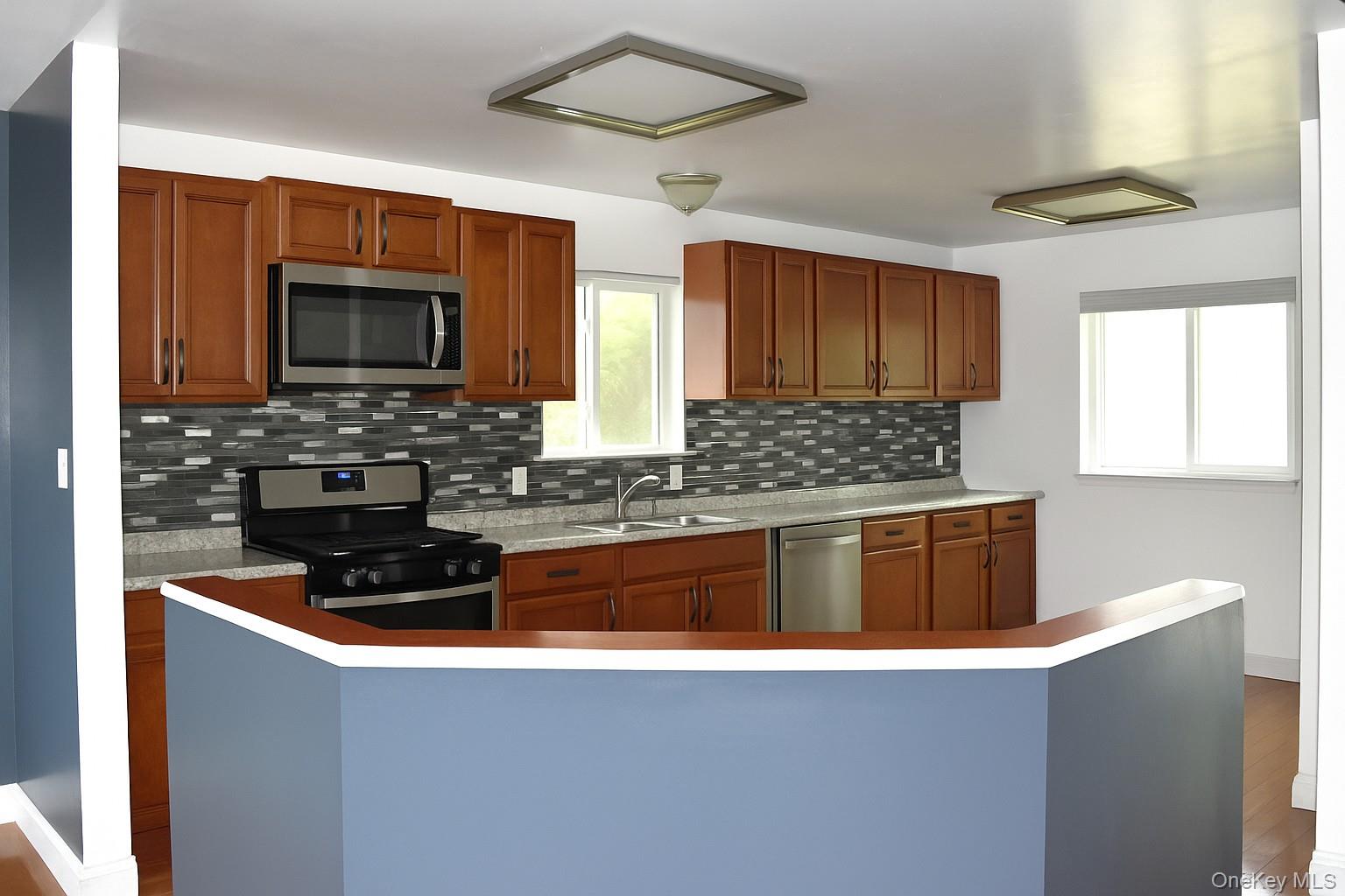 21 Walden Estates Road Walden, NY 12586 - Photo 6 of 32 Kitchen featuring backsplash, light countertops, appliances with stainless steel finishes, dark wood-type flooring, and healthy amount of natural light