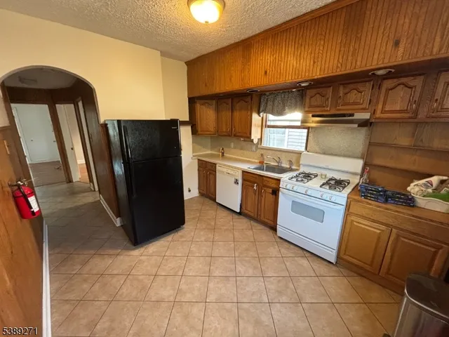 a kitchen with stainless steel appliances granite countertop a refrigerator a stove and a sink
