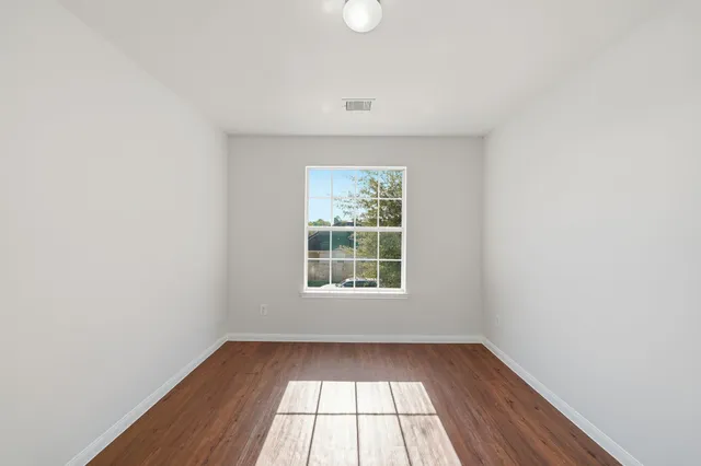 an empty room with wooden floor and windows