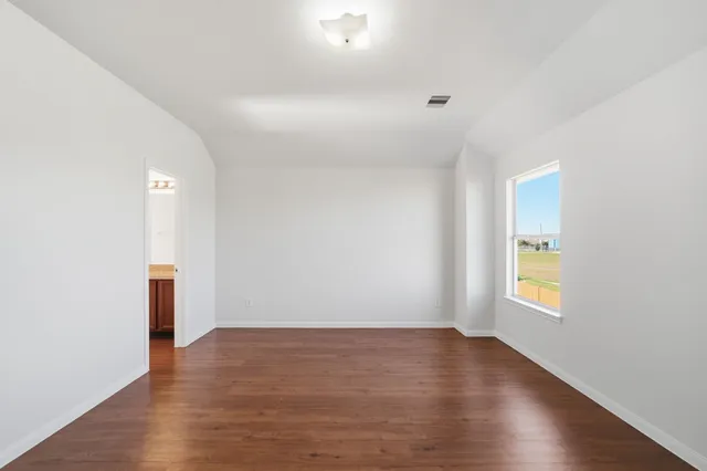 a view of an empty room with window and wooden floor