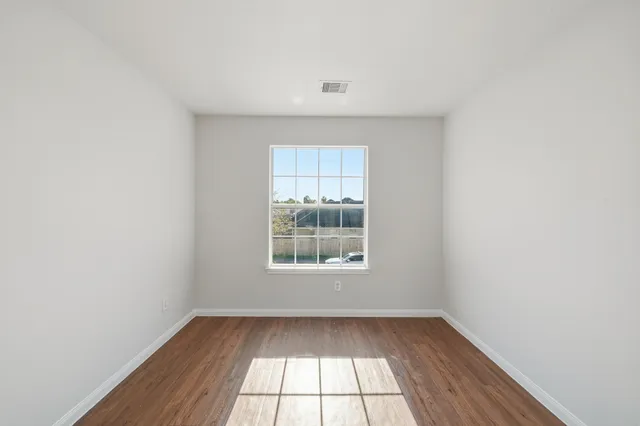 an empty room with wooden floor and windows