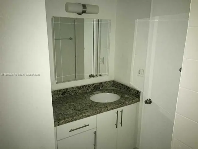 a bathroom with a granite countertop sink and a mirror