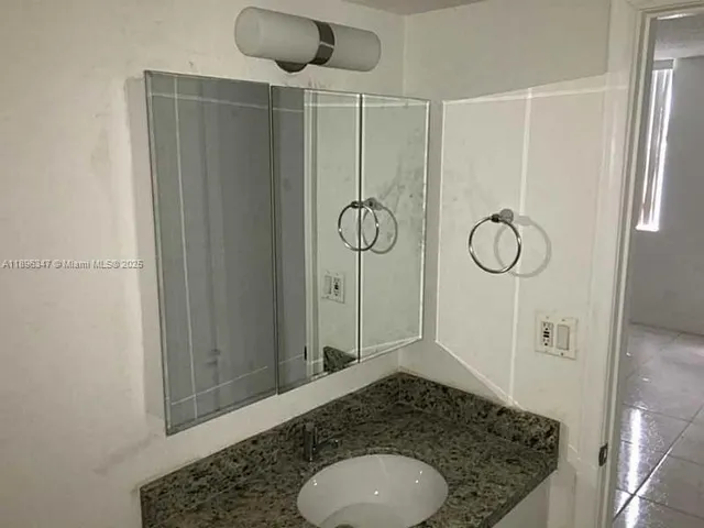 a bathroom with a granite countertop sink a mirror and shower