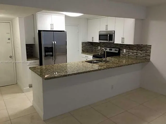 a kitchen with granite countertop a refrigerator and a stove top oven