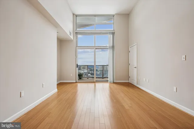 an empty room with wooden floor mirror and windows