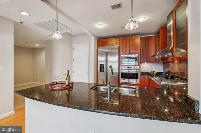 a kitchen with kitchen island granite countertop a sink a counter top space appliances and cabinets