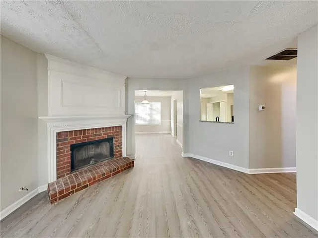 an empty room with wooden floor fireplace and windows