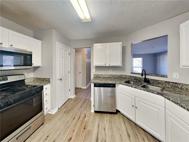 a kitchen with granite countertop a sink cabinets and stainless steel appliances