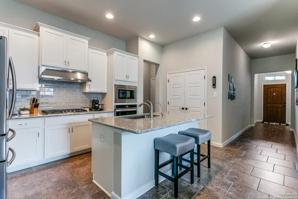 a kitchen with kitchen island granite countertop a stove a sink a refrigerator and cabinets