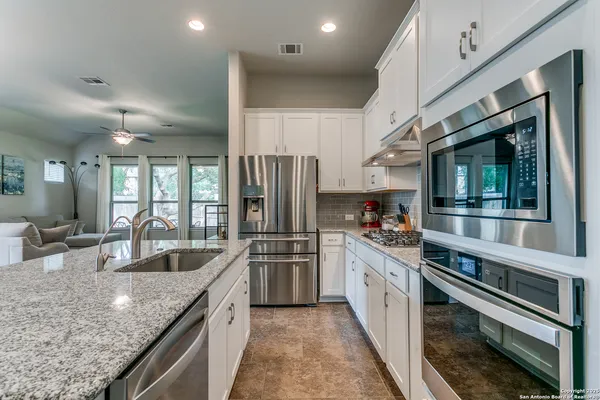 a kitchen with stainless steel appliances granite countertop a sink and a refrigerator