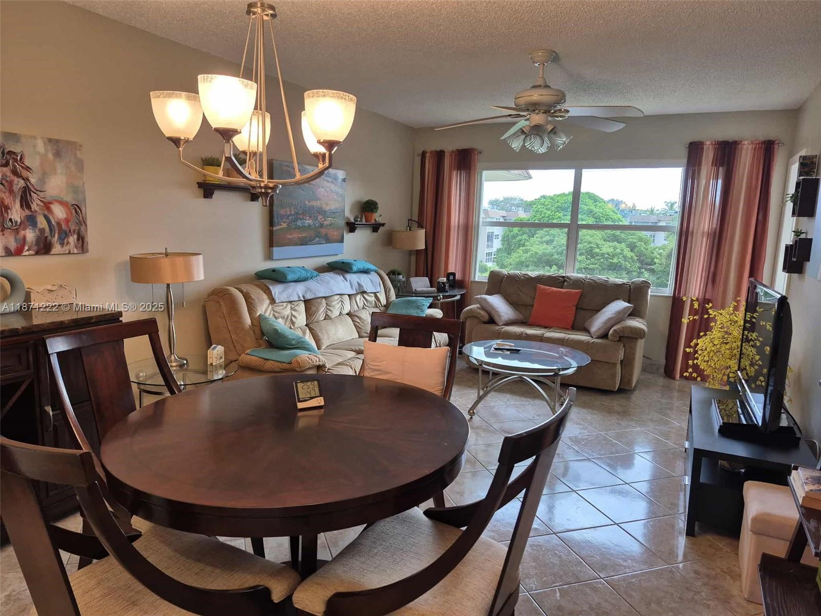 3400 Northwest 48th Avenue, Unit 607 Lauderdale Lakes, FL 33319 - Photo 2 of 17 a dining room with furniture a large window and a chandelier