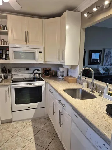 a kitchen with granite countertop a sink a stove and cabinets