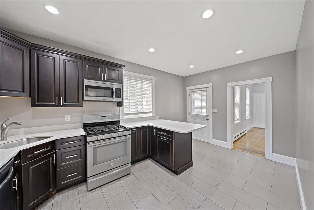 23 Reed Place Whitman, MA 02382 - Photo 5 of 35 a kitchen with kitchen island granite countertop a stove sink and cabinets