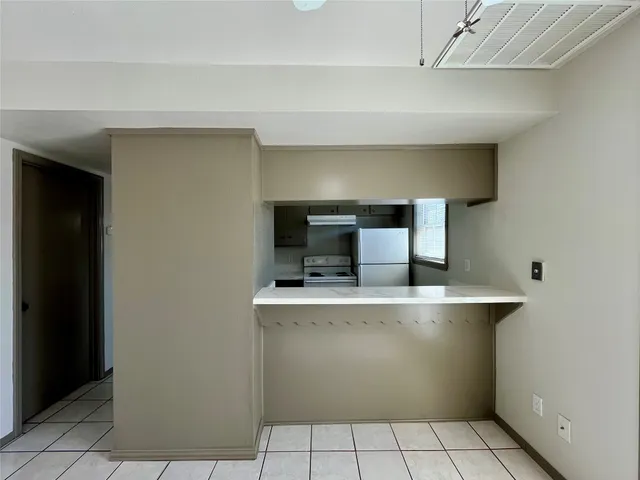 a view of a kitchen with a stove wooden cabinets and a refrigerator