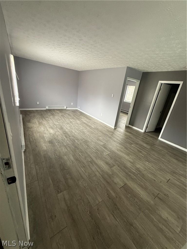 662 Sumner Street Akron, OH 44311 - Photo 2 of 10 Spare room featuring dark wood-style floors, a textured ceiling, and a baseboard radiator