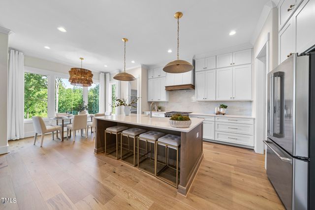 a kitchen with stainless steel appliances granite countertop a stove a sink dishwasher a refrigerator and a dining table with wooden floor