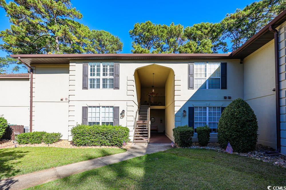 View of front of property featuring stairs and a front lawn