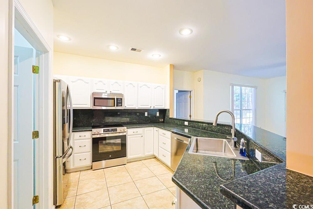 401 Pipers Lane, Unit 401 Myrtle Beach, SC 29575 - Photo 4 of 40 Kitchen featuring appliances with stainless steel finishes, decorative backsplash, light tile patterned flooring, white cabinetry, and a peninsula