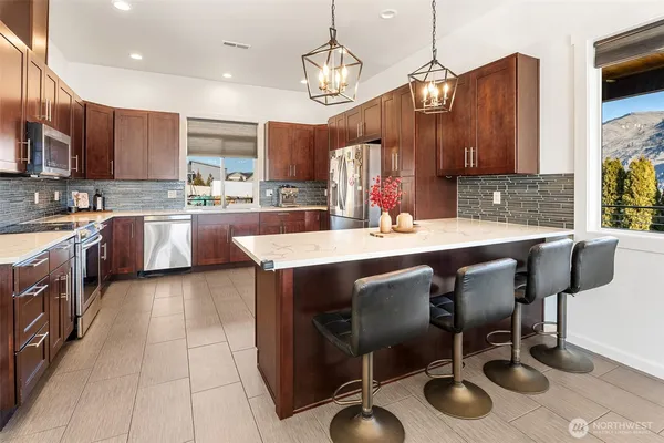a kitchen with stainless steel appliances a refrigerator a sink a stove and chairs