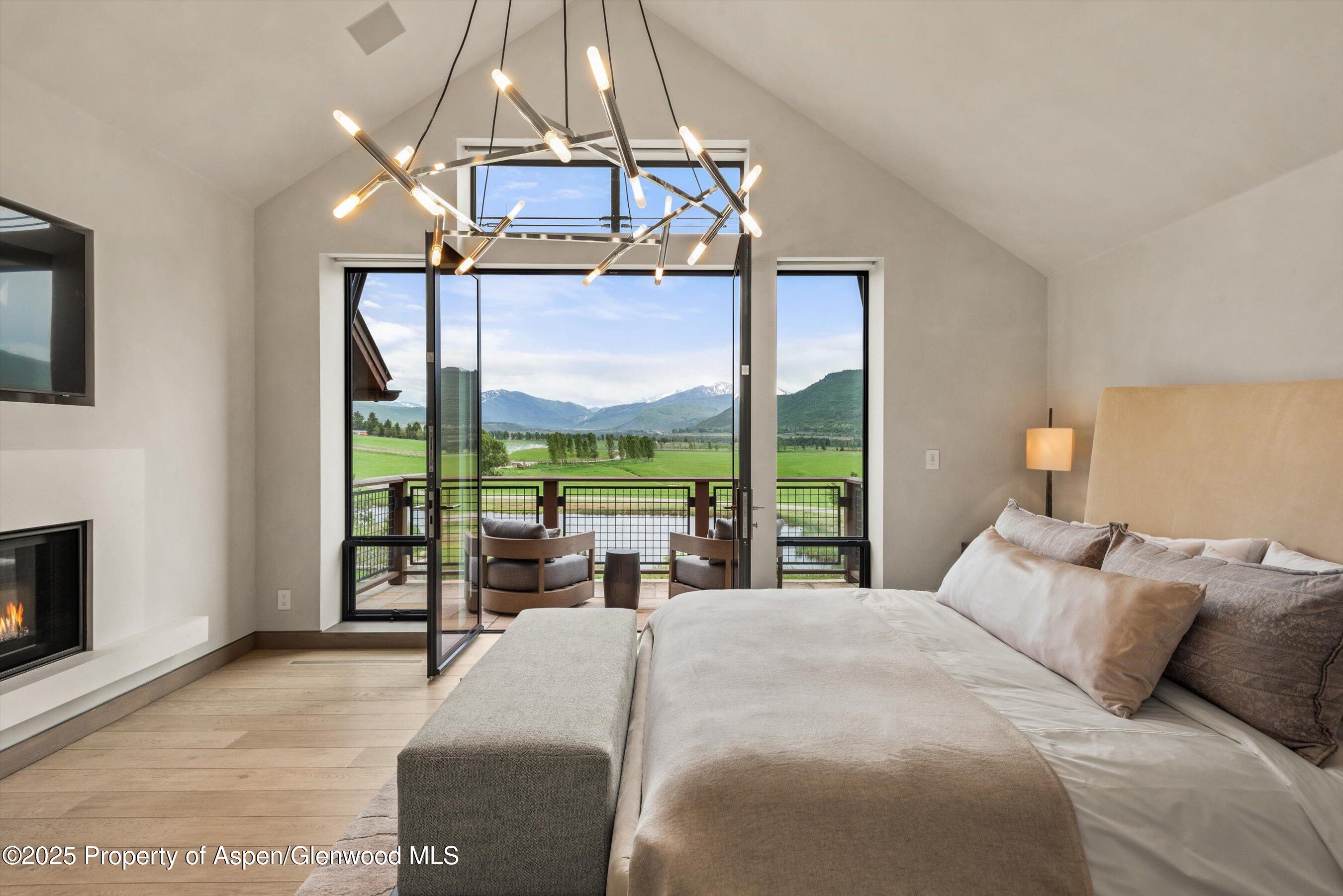 31 Aspen Valley Ranch Road Woody Creek, CO 81656 - Photo 22 of 52 a bedroom with a bed a chandelier and a large window