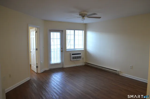 an empty room with wooden floor fan and windows
