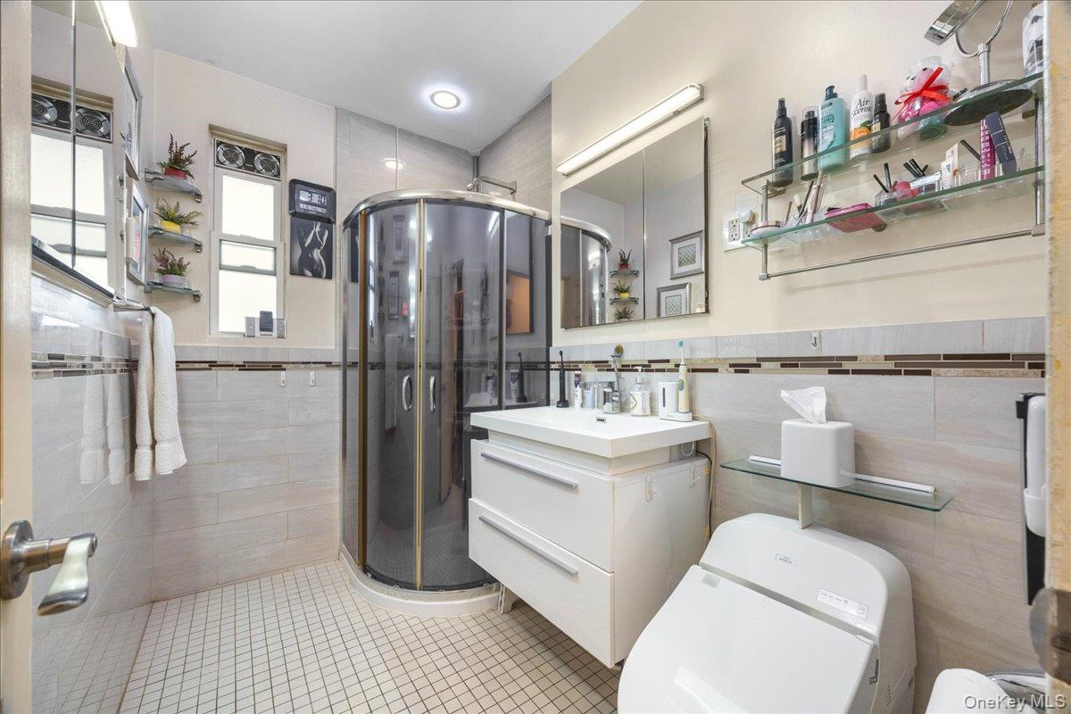1015 Old Boston Post Road, Unit 2C Mamaroneck, NY 10543 - Photo 18 of 26 Bathroom with vanity, tile walls, a shower stall, light tile patterned floors, and a wainscoted wall