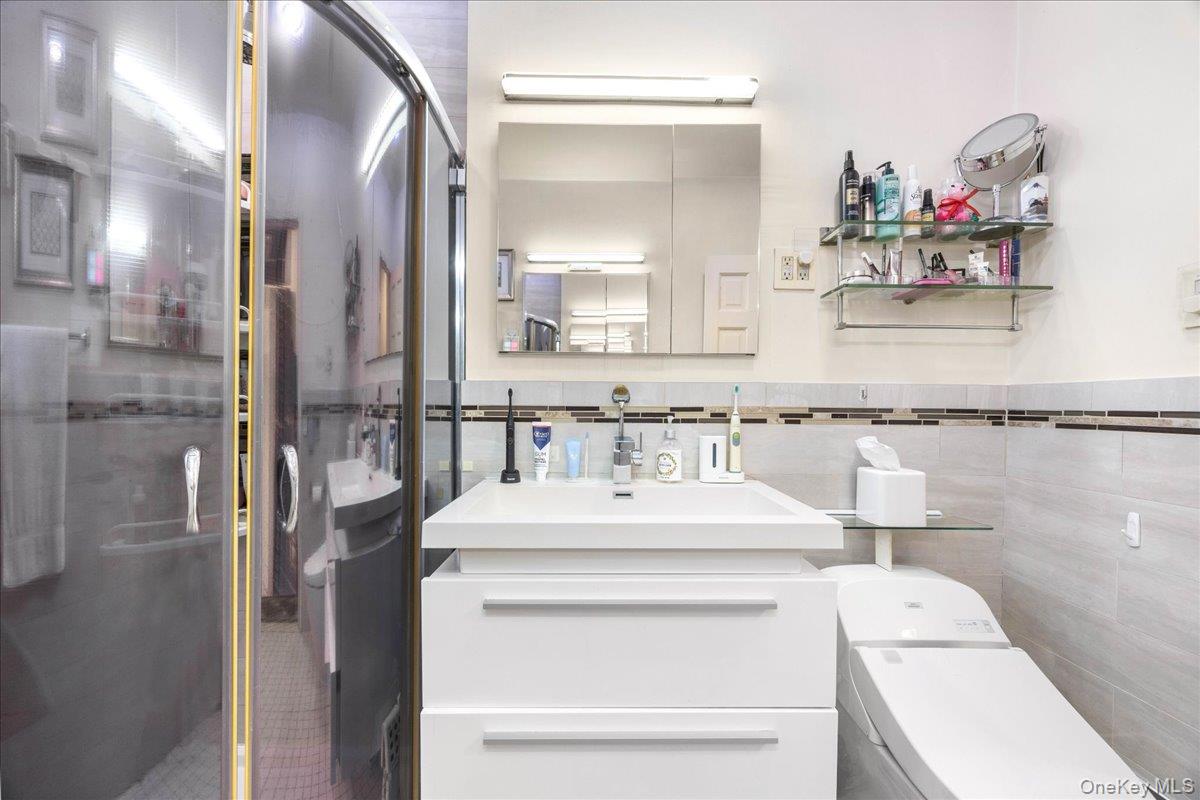 1015 Old Boston Post Road, Unit 2C Mamaroneck, NY 10543 - Photo 19 of 26 Bathroom with vanity, tile walls, a stall shower, and a wainscoted wall