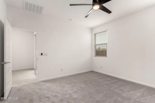 an empty room with a ceiling fan and carpet