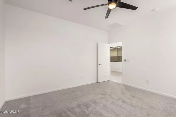 an empty room with a ceiling fan and carpet