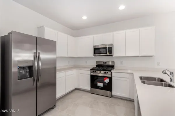 a kitchen with stainless steel appliances granite countertop a refrigerator a stove a sink and a microwave