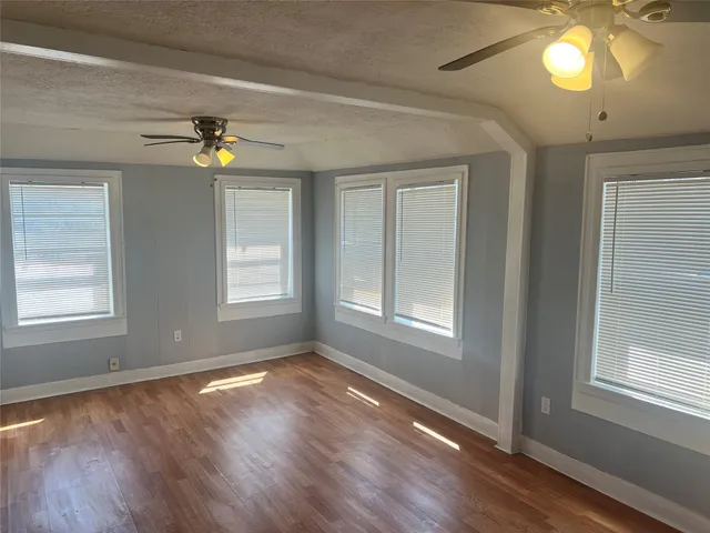 a view of an empty room with a window and wooden floor