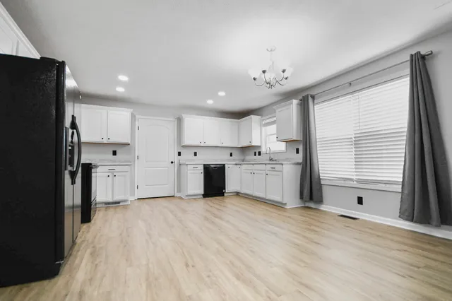 a large kitchen with kitchen island a sink a center island stainless steel appliances and a window