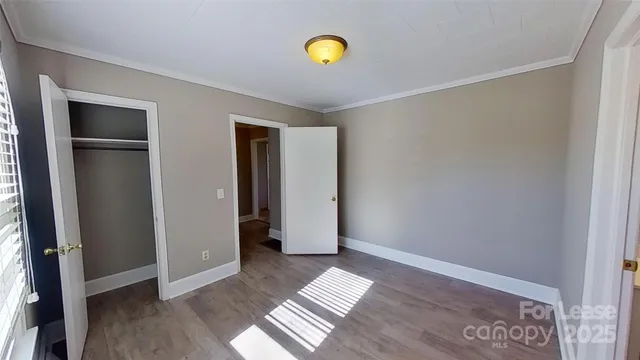 a view of an empty room with wooden floor and closet