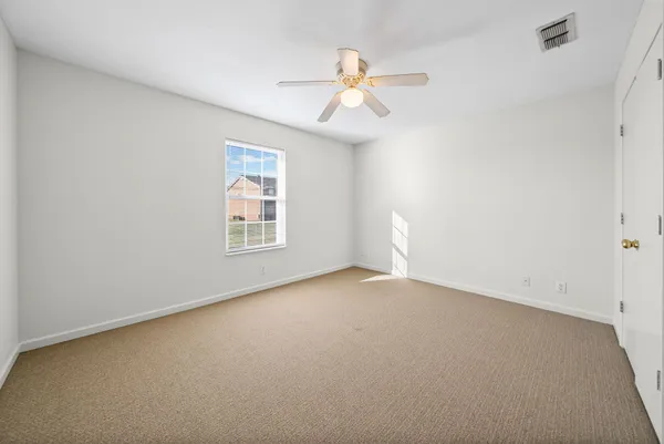 an empty room with windows and fan