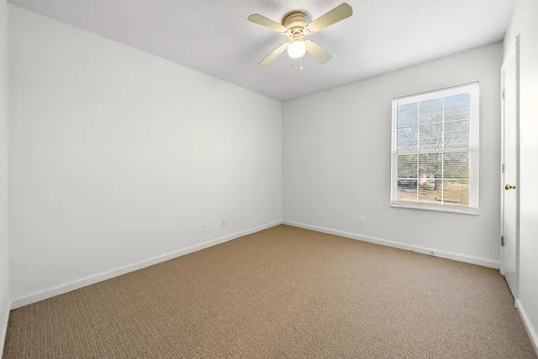 an empty room with a window and a fan