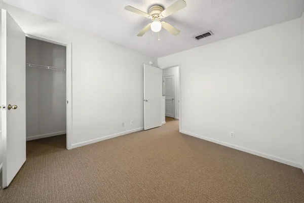 an empty room with closet and a chandelier fan