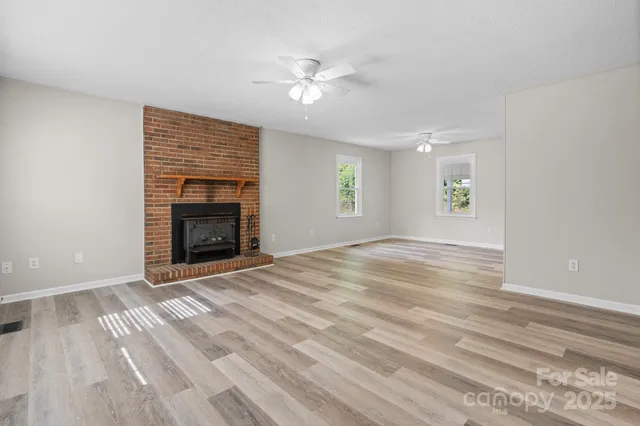 an empty room with windows and fireplace