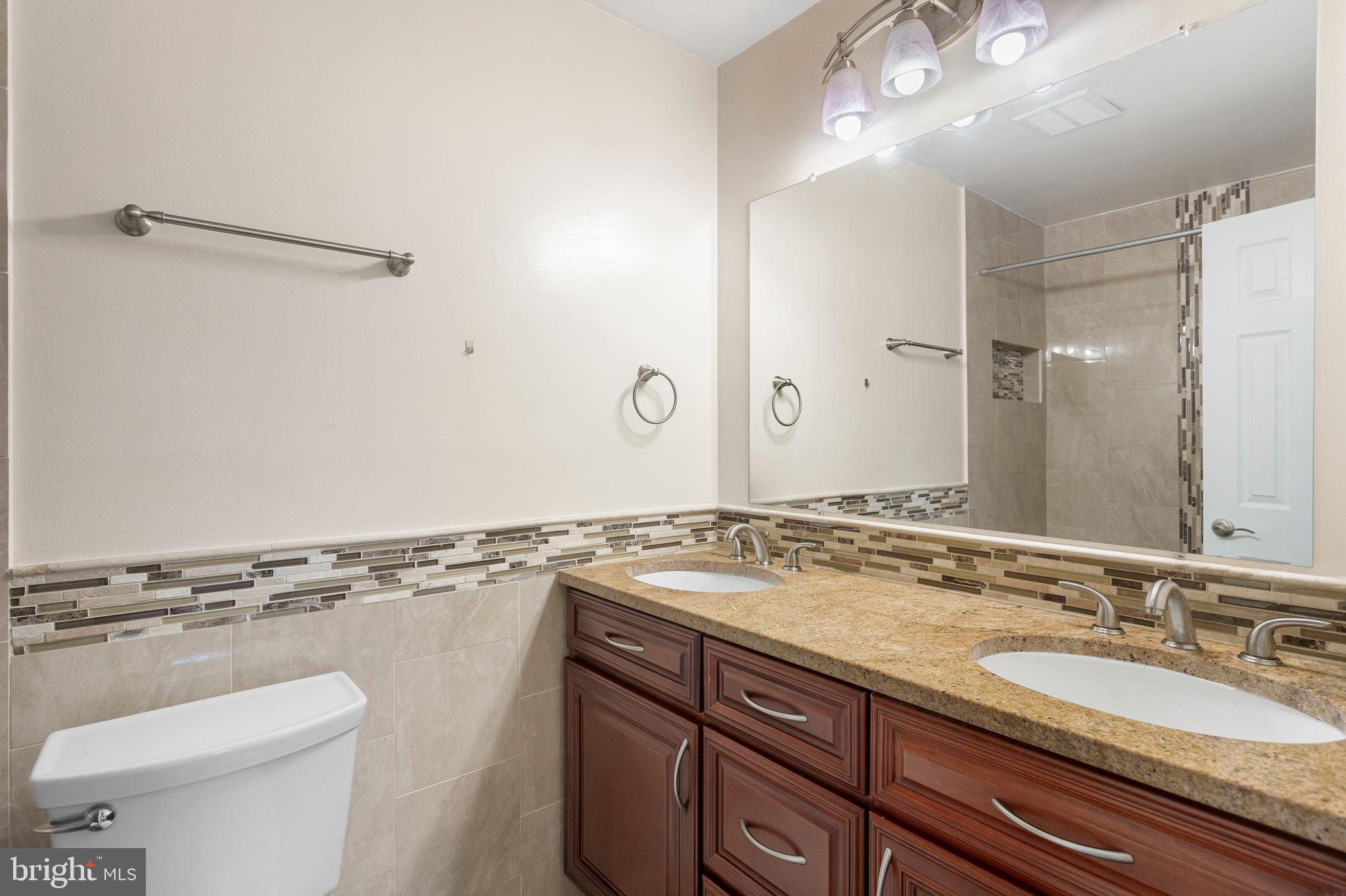 8403 Harker Drive Potomac, MD 20854 - Photo 14 of 33 a bathroom with a granite countertop sink a toilet and a mirror