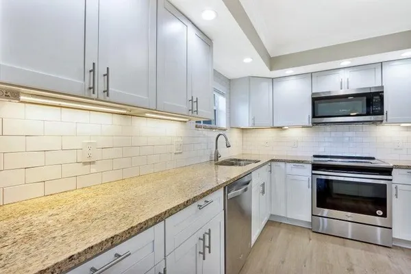a kitchen with stainless steel appliances granite countertop a sink stove and microwave