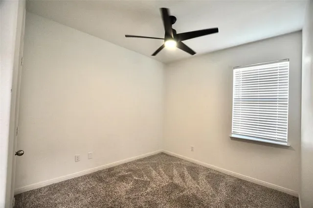 an empty room with a window and a fan