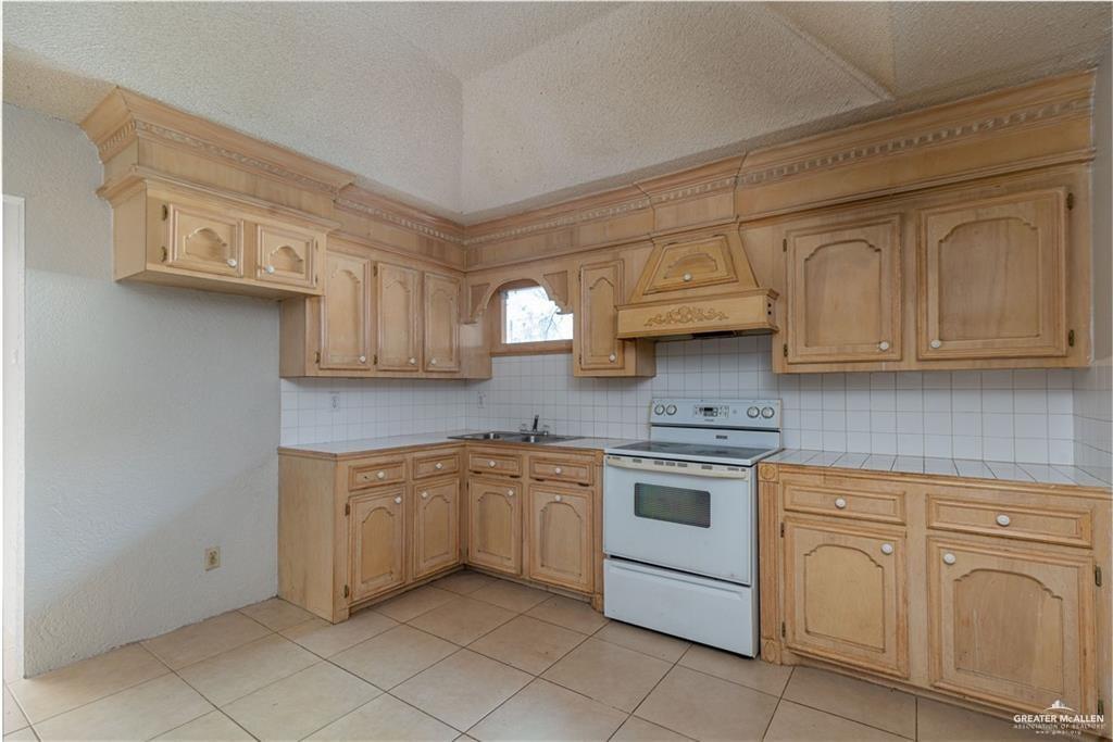 933 East 4th Street Roma, TX 78584 - Photo 4 of 15 a kitchen with white cabinets and white appliances