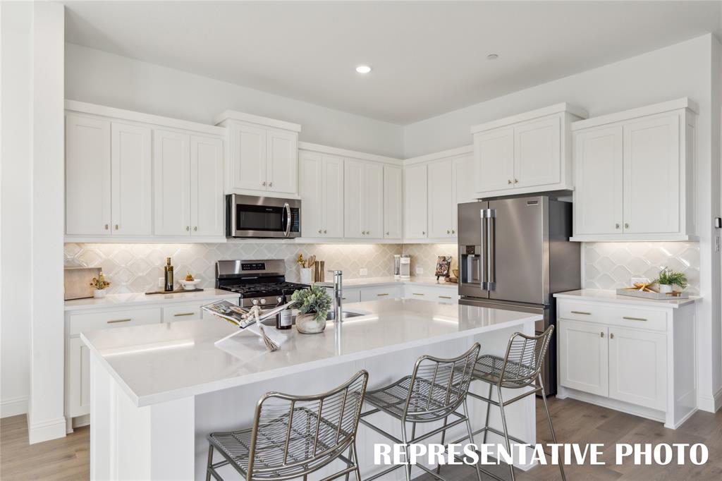 1303 Rooted Road Frisco, TX 75033 - Photo 6 of 14 a kitchen with stainless steel appliances a sink a stove a microwave a refrigerator and cabinets