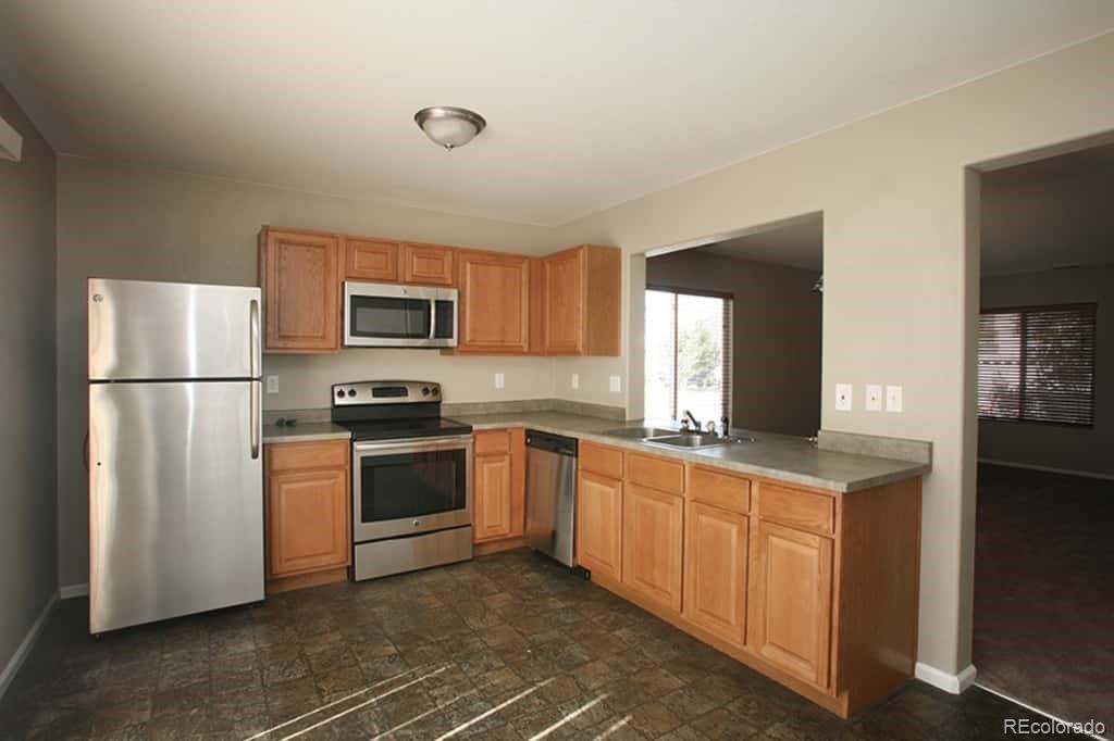 4067 Andes Way Denver, CO 80249 - Photo 4 of 4 a kitchen with stainless steel appliances granite countertop a refrigerator a stove a sink and a microwave