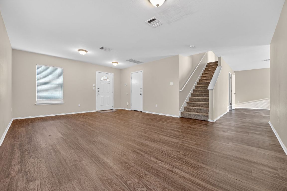 13205 Vizquel Loop Del Valle, TX 78617 - Photo 9 of 31 an empty room with wooden floor and staircase