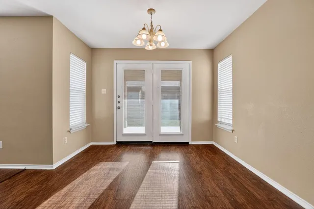 an empty room with wooden floor cabinet and windows
