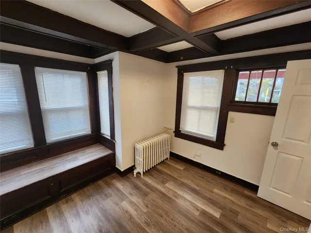 a view of an empty room with wooden floor and windows