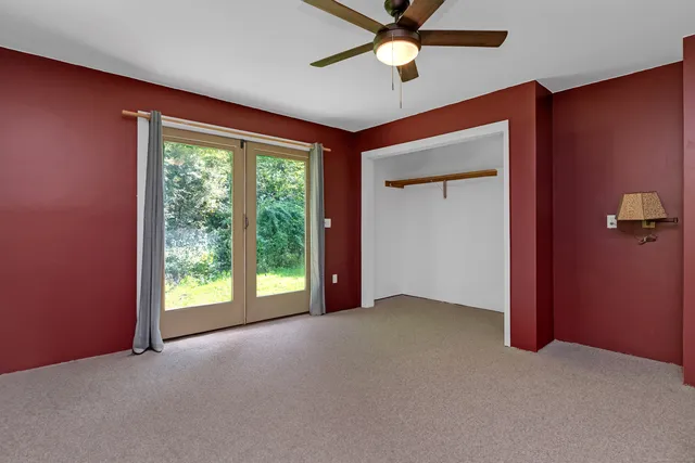 an empty room with windows and fan