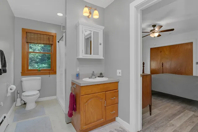 a bathroom with a granite countertop sink a toilet and shower