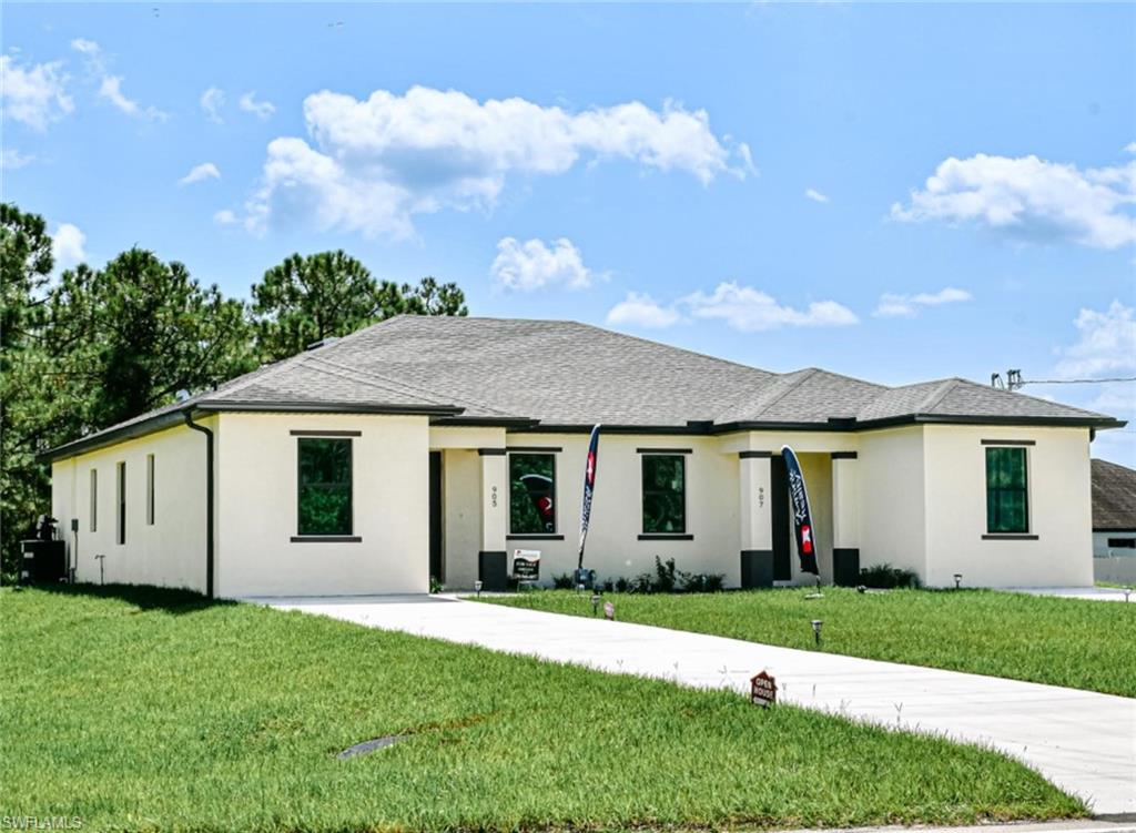 907 Homestead Road South Lehigh Acres, FL 33974 - Photo 1 of 43 Contemporary single-story residence with a light stucco exterior and dark trim accents