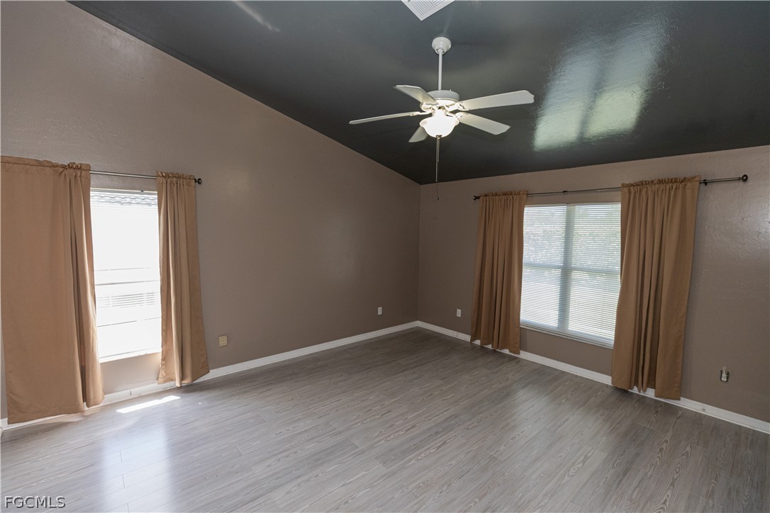 7500 Cameron Circle Fort Myers, FL 33912 - Photo 13 of 21 an empty room with wooden floor chandelier fan and windows